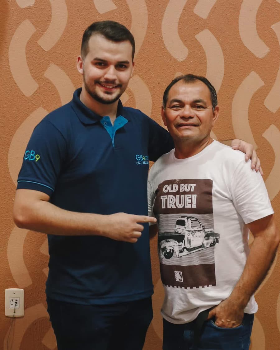 Giordano Bruno, de camisa polo azul da GB9, sorrindo e apontando para o homem ao seu lado